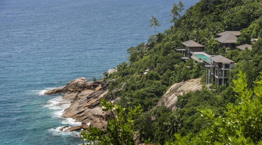 Four Seasons Resort Seychelles privātās villas piekrastē, ieskautas tropu zaļumos ar skatu uz okeānu.
