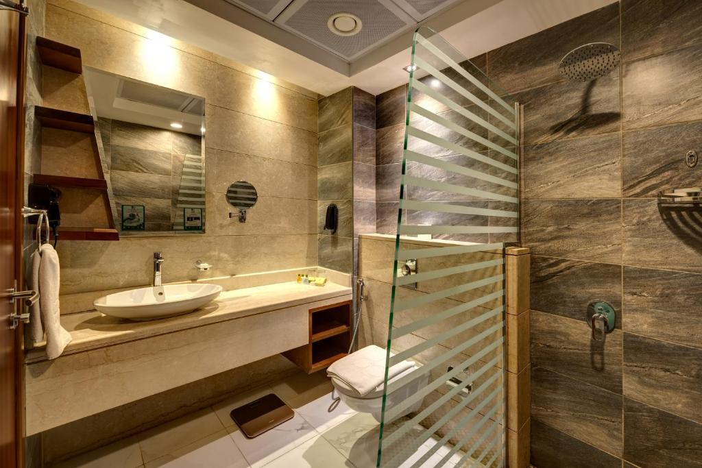 Rose Park Hotel Al Barsha modern bathroom with glass shower.