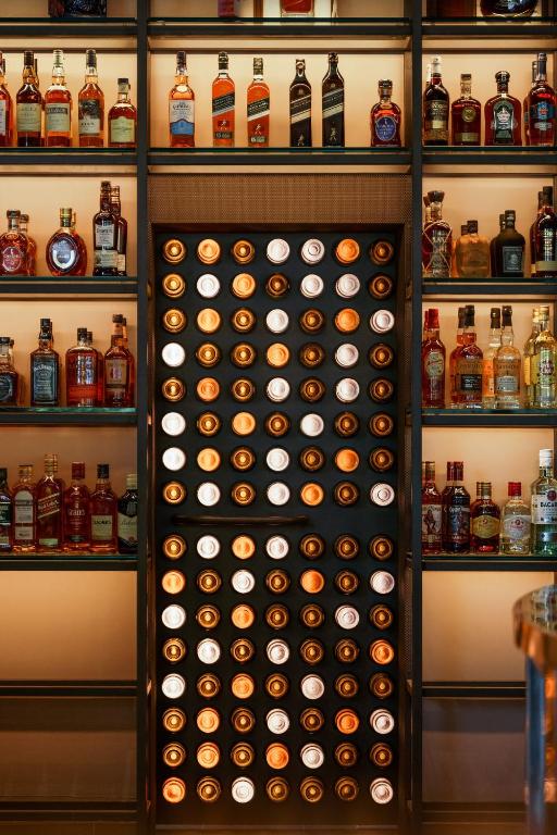 Alus un stipro alkoholisko dzērienu plaukts ar elegantu apgaismojumu un lielu pudelēm.