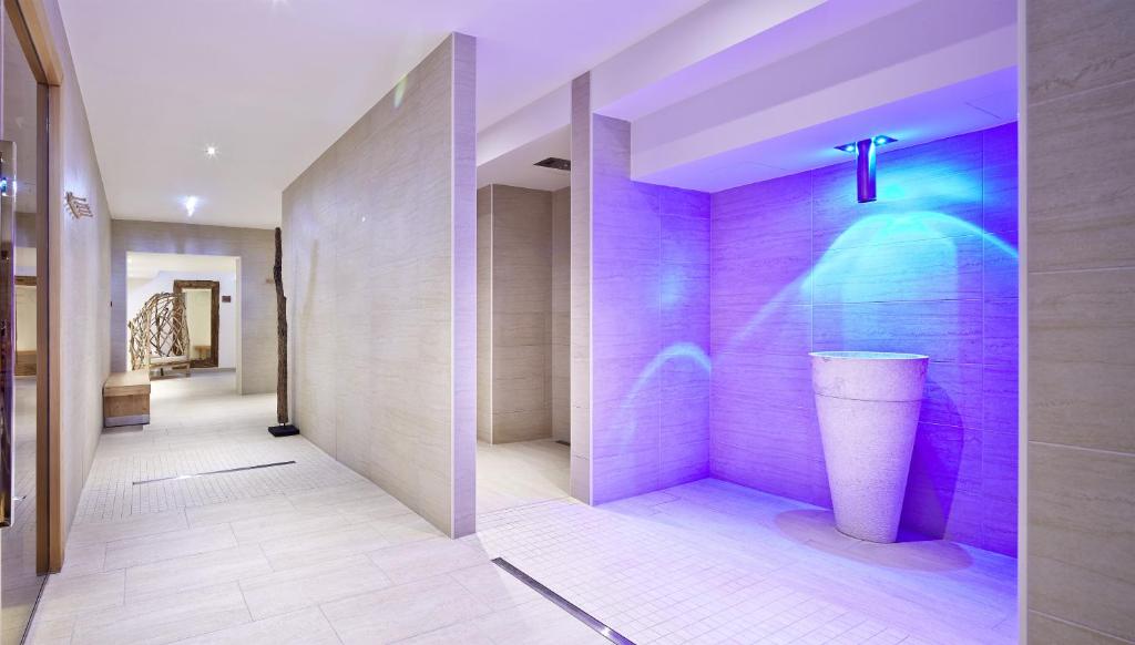 Mūsdienīga spa telpa ar relaksējošiem zilo gaismu efektiem un elegantu akmens fontānu, radot mierīgu atmosfēru.