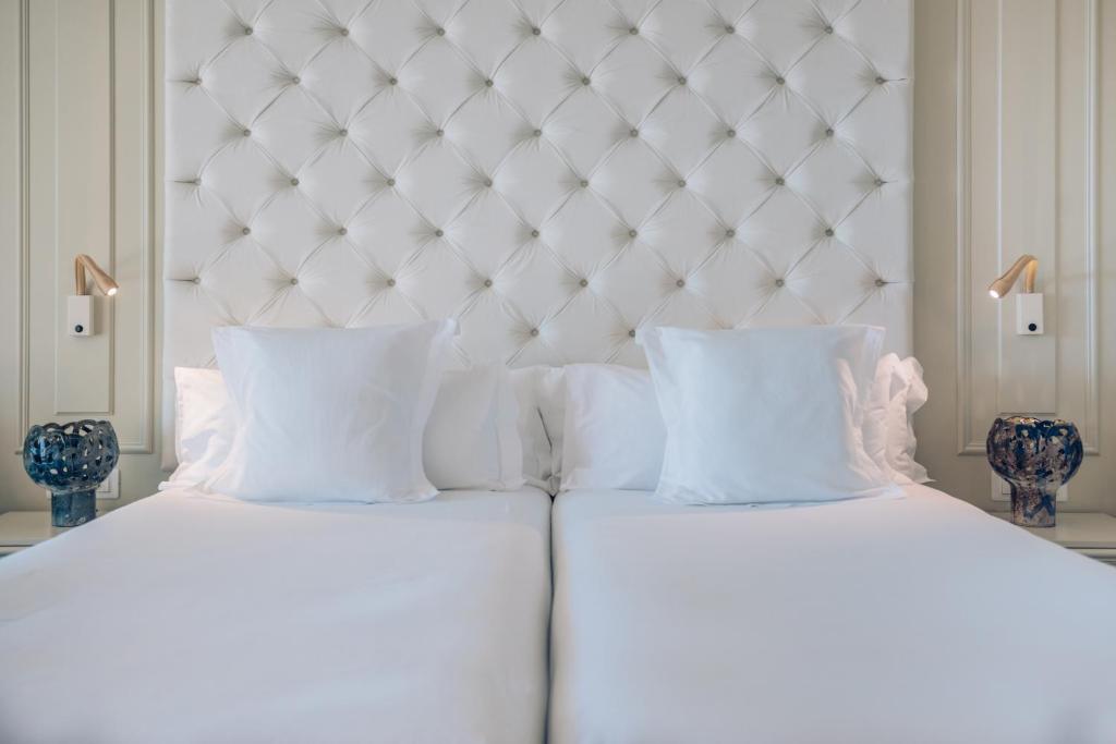 Mūsdienīga guļamistaba ar baltu gultu, izsmalcinātu galvgalvi un dekoratīvām lampām. Eleganta un komfortabla vide relaksācijai.