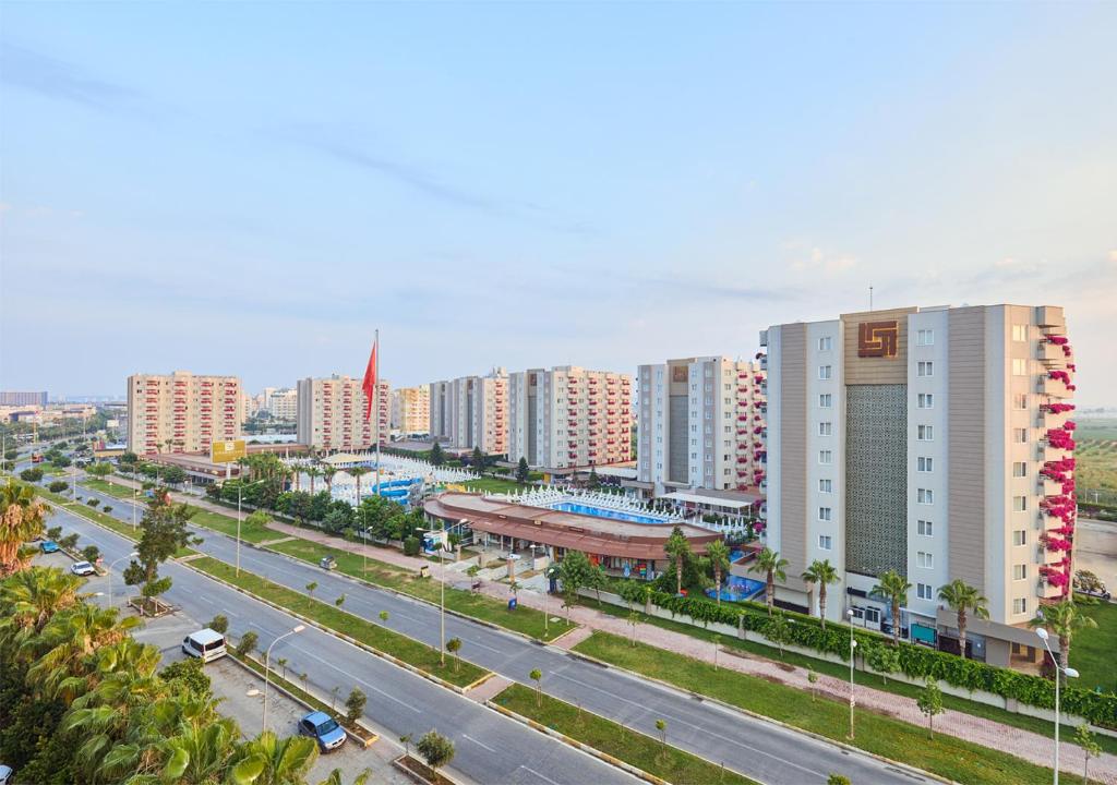 Mūsdienīga viesnīcu komplekss ar baseinu un apzaļumotu teritoriju, kas atrodas blakus ceļam. Apkārt ir daudzdzīvokļu mājas un plašs, atvērts debesis ar zilu fona.