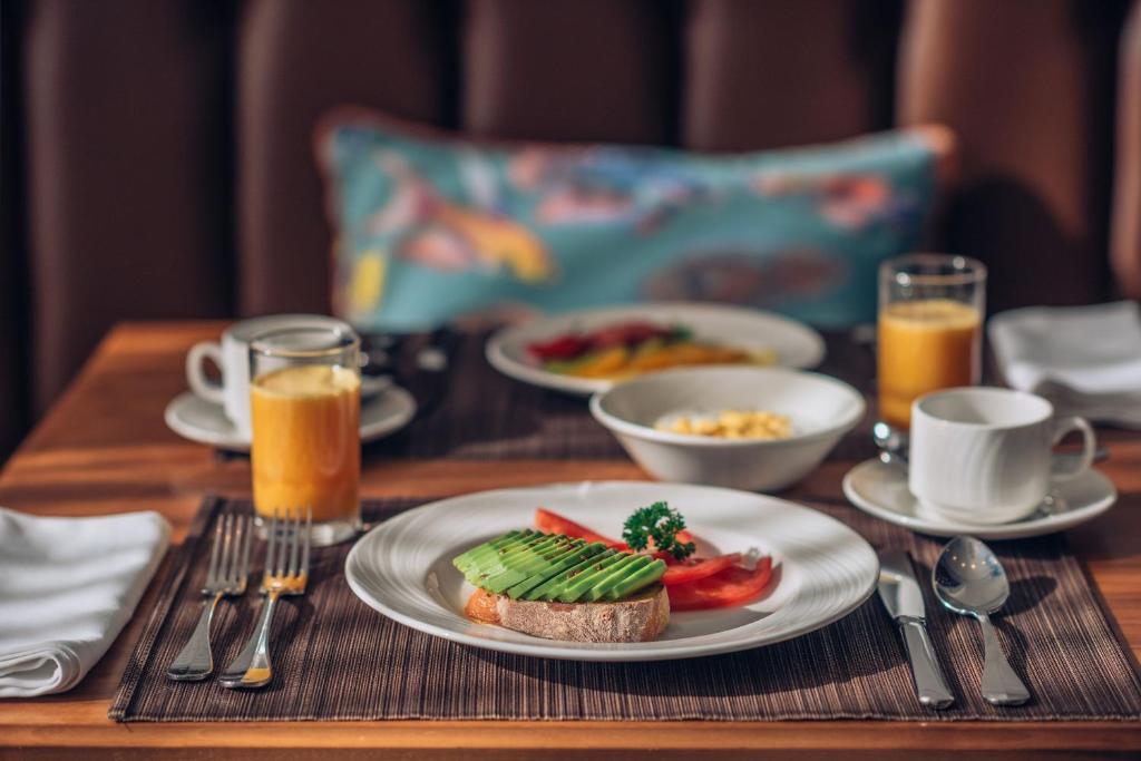 Skaista brokastu galda iestatījums ar grauzdiņu, uz kura ir avokado, tomātiem un pētersīļiem, kopā ar augļu salātiem, jogurtu un dzērieniem. Ideāla dienas sākuma aina.