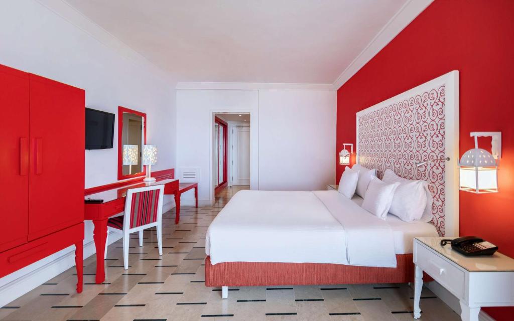 Mūsdienīga guļamistaba ar spilgti sarkanu sienu un elegantu interjeru, iekļaujot sarkanas mēbeles un gaismas elementus. Ideāla izvēle komfortablai atpūtai.