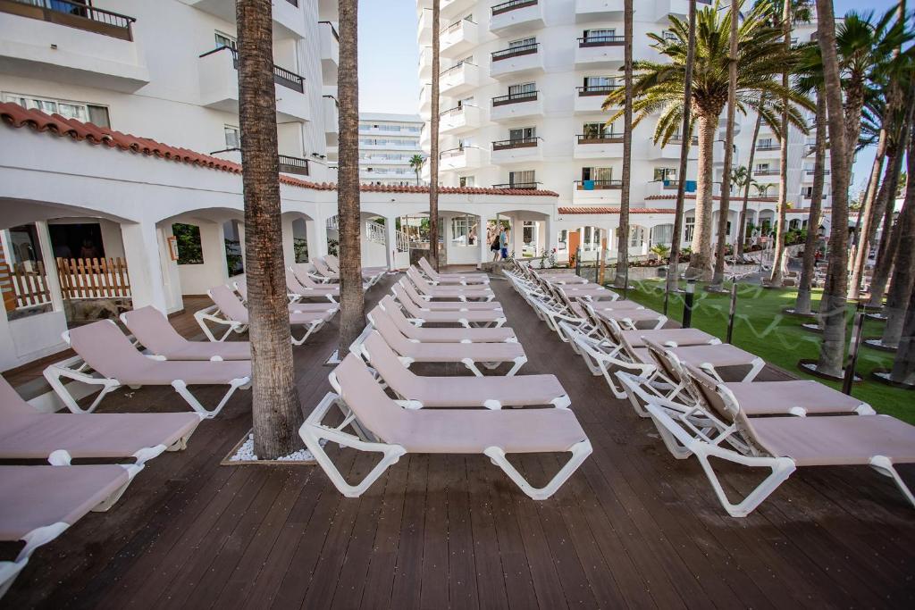Atpūtas zona ar saulessargiem un palmām viesnīcā, kas piedāvā relaksējošu atmosfēru un ērtu atpūtu. Ideāla vieta, kur baudīt sauli un dabu.