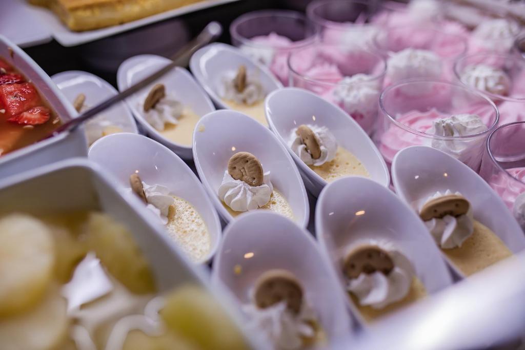Saldējumu un desertu bufete ar krēmīgu pudiņu un putukrējumu, rotātu ar cepumiem. Dažādi saldumi, tostarp augļu salāti un smalkmaizītes.