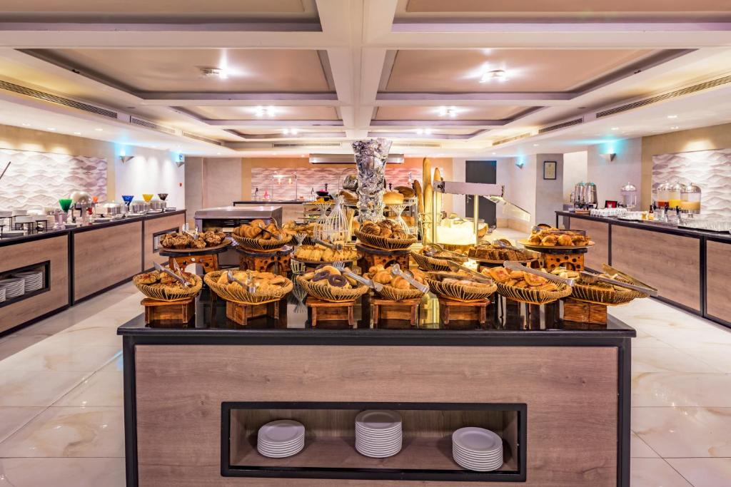 Elegants bufetes galds ar dažādiem uzkodu un maizes izstrādājumiem, izgaismots modernā restorānā. Interjers ar gaišiem toņiem un mūsdienīgu dizainu rada patīkamu atmosfēru.