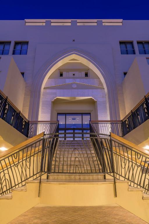 Eleganta ieeja ar arku un kāpnēm, kas ved uz durvīm. Gaismas apgaismojums izceļ arhitektūras detaļas.