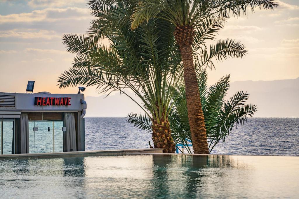 Pludmales kafejnīcas "HEATWAVE" skats ar palmām un mierīgu jūras ainavu. Ideāla vieta atpūtai un relaksācijai, izbaudot saulainus mirkļus pie ūdens.