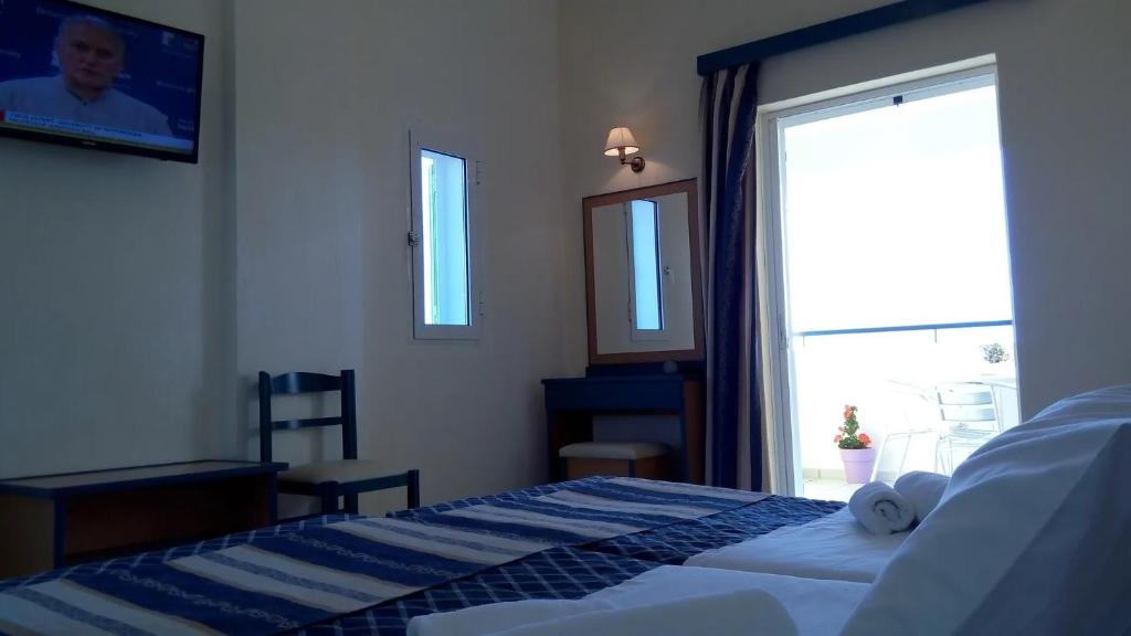 Mūsdienīga viesnīcas numura iekārtojums ar gultu, televizoru un skatu uz balkonu. Telpā ir rakstāmgalds un spogulis, radot ērtu un mājīgu atmosfēru.