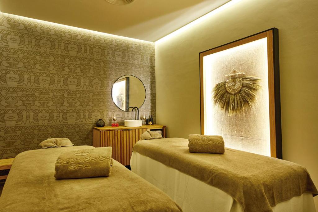 Relaksējoša spa istaba ar divām masāžas galdiem, mīkstiem dvieļiem un dekoratīvu sienu ar ģeometriskiem rakstiem. Interjerā ir moderni apgaismojumi un mākslas elements.