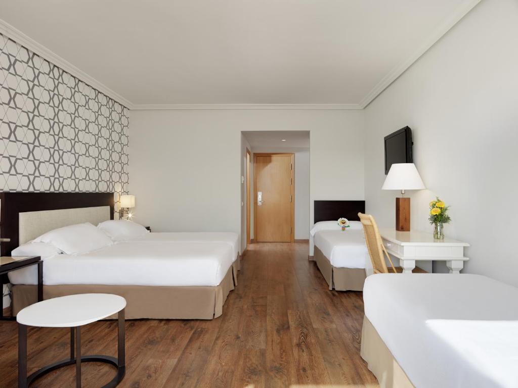 Moderns viesnīcas numurs ar divām gultām, galdu un krēslu, kā arī televizoru un ziedu pušķi uz galda. Interjerā ir gaišas krāsas un koka grīda.