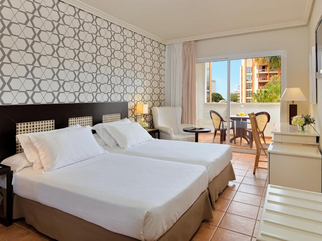 Grezns viesnīcas numurs ar divām gultām, gaišām krāsām un modernu dizainu, kā arī balkonu ar skatu uz dārzu. Iekārtots ar ērtām mēbelēm un dekoratīvām detaļām.