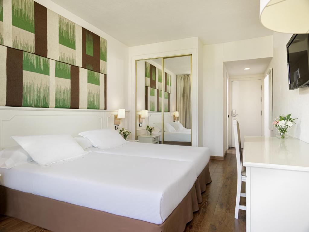 Moderns viesnīcas numurs ar divām gultām, elegantu dizainu un dabīgām krāsām, kas rada mājīgu atmosfēru. Numurā ir spogulis, televizors un krēsls ar galdu.