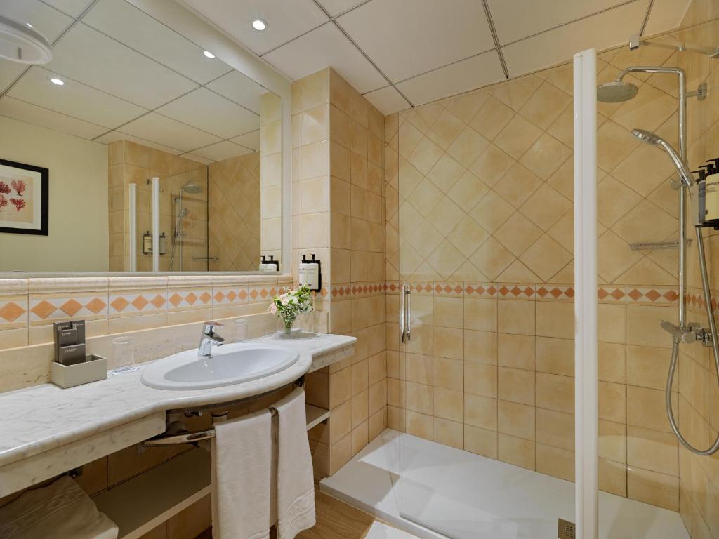 Mūsdienīgs vannas istabas interjers ar dušas kabīni, akmens izlietni un elegantu spoguli, kas rada mājīgu atmosfēru. Vannas istaba ir iekārtota ar neitrālām krāsām un modernām iekārtām.