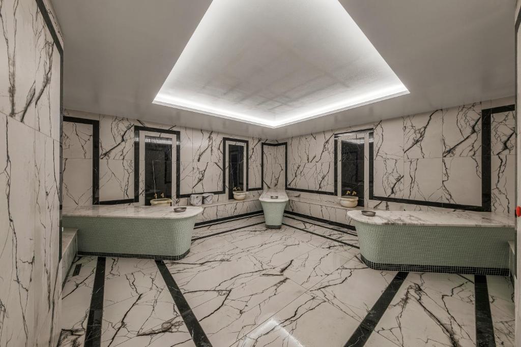 Mūsdienīgs vannas istabas interjers ar marmora sienām un elegantām detaļām. Telpai raksturīga minimālistiska estētika un gaiša apgaismojuma dizains.