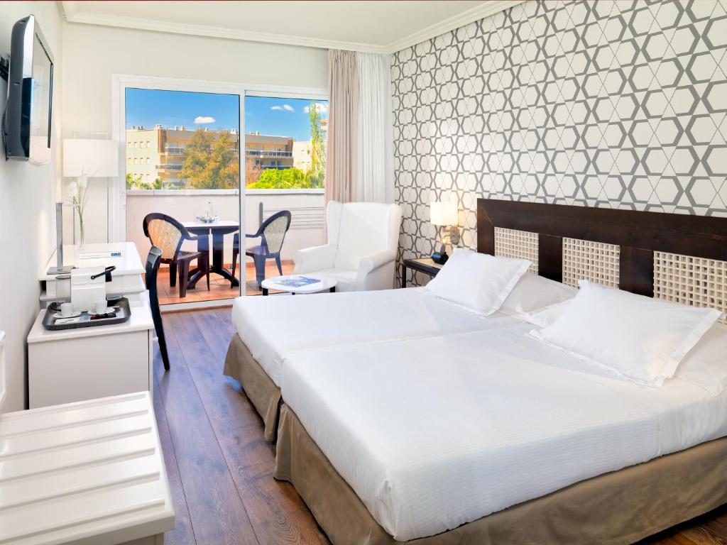 Mūsdienīgs viesnīcas numurs ar divām atsevišķām gultām, gaisīgu interjeru un skatu uz terasi, kurā ir galdiņš un krēsli. Ideāls vieta relaksācijai un atpūtai.