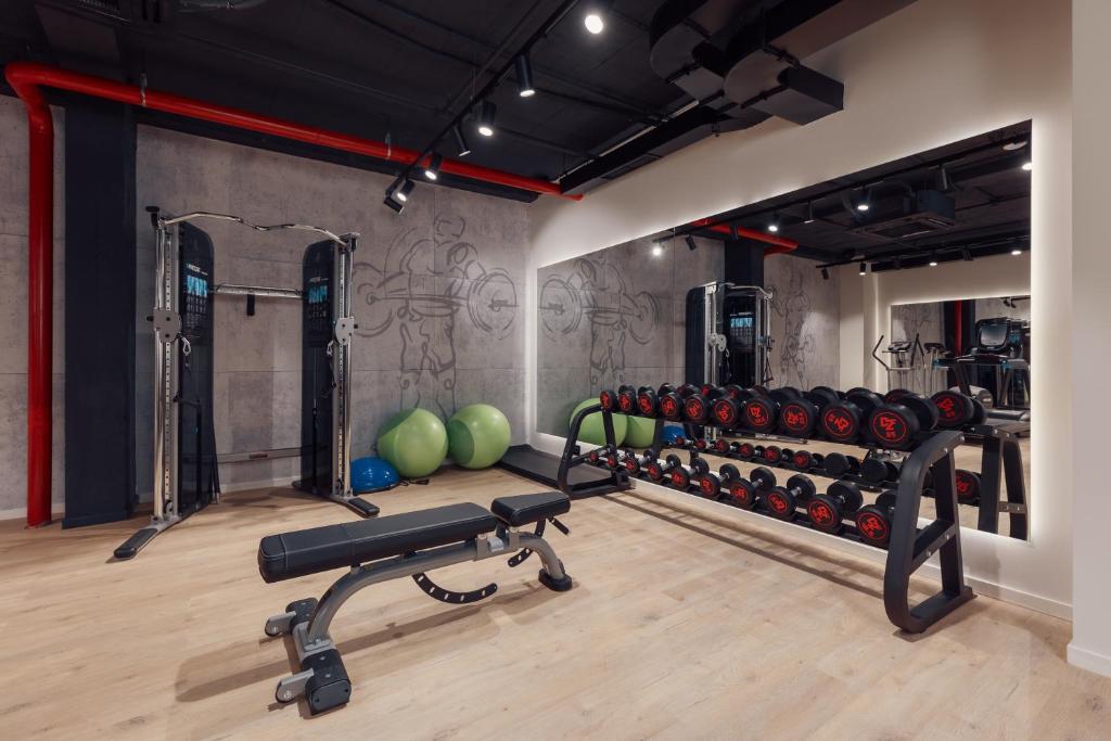Mūsdienīgs sporta zāles interjers ar svaru staciju, hantelēm un vingrošanas bumbām, kas nodrošina ideālu vidi treniņiem. Spacious and well-equipped gym setting designed for effective workouts.