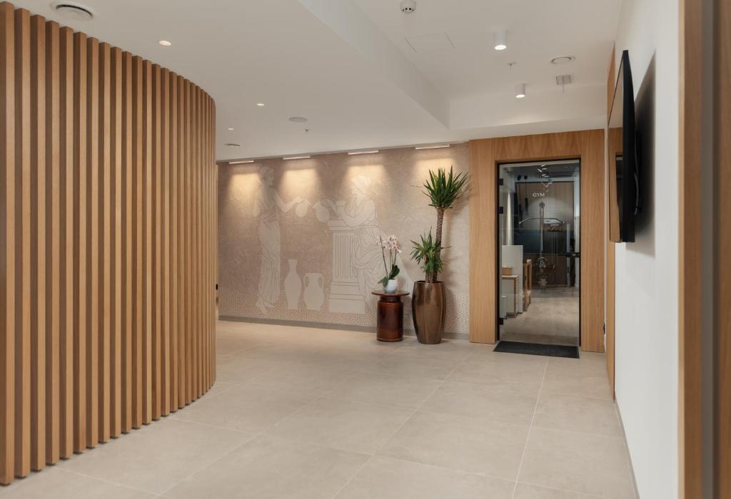 Mūsdienīgs un elegants koridors ar koka apdari un augu elementiem, kas vērš uzmanību uz sporta zāles ieeju. Sienas rotā mākslinieciskas atainojumi un gaismas, radot patīkamu atmosfēru.