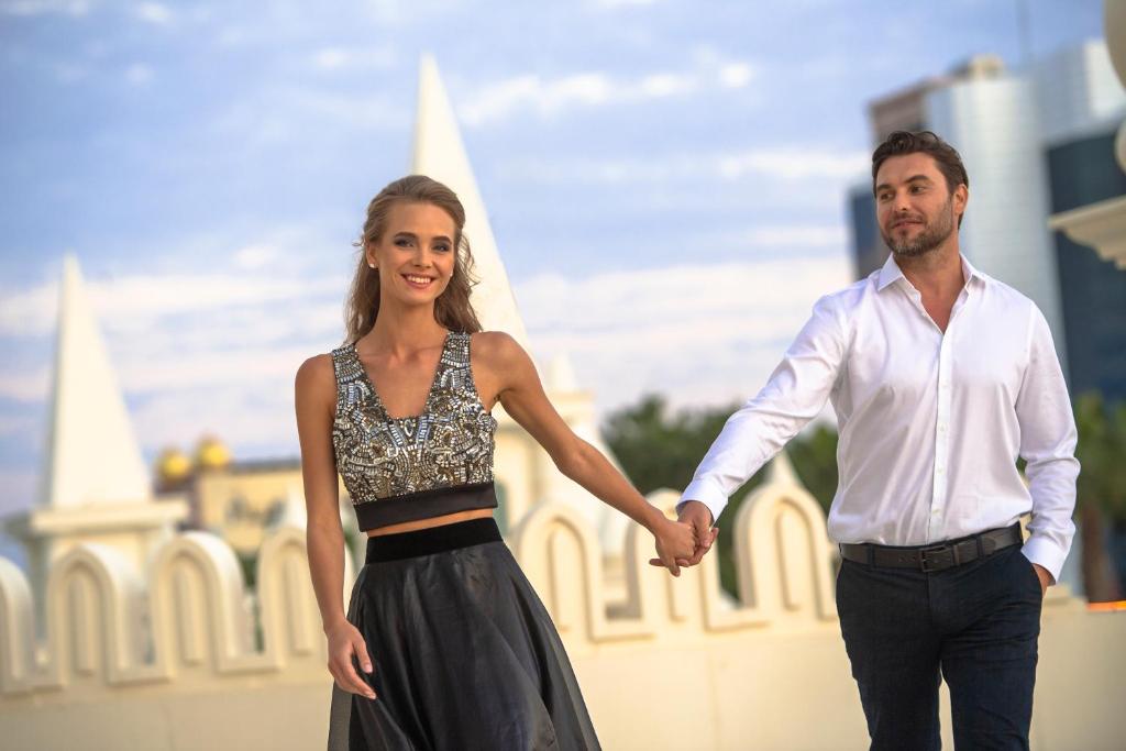 Pāris, kas turas pie rokas, izbaudot romantisku brīdi pie Sentido Kamelya Selin Luxury Resort & SPA.