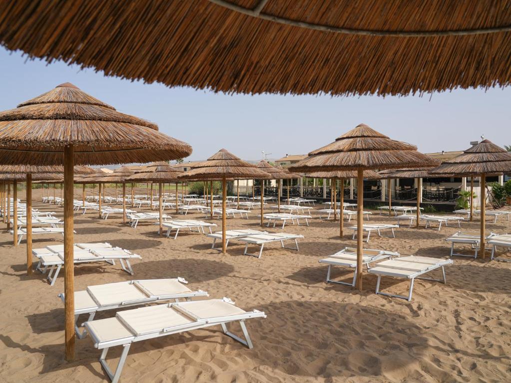 Pludmales ainava ar saulessargiem un atpūtas krēsliem, kas izvietoti smiltīs. Ideāla vieta relaksācijai un atpūtai saulainā dienā.