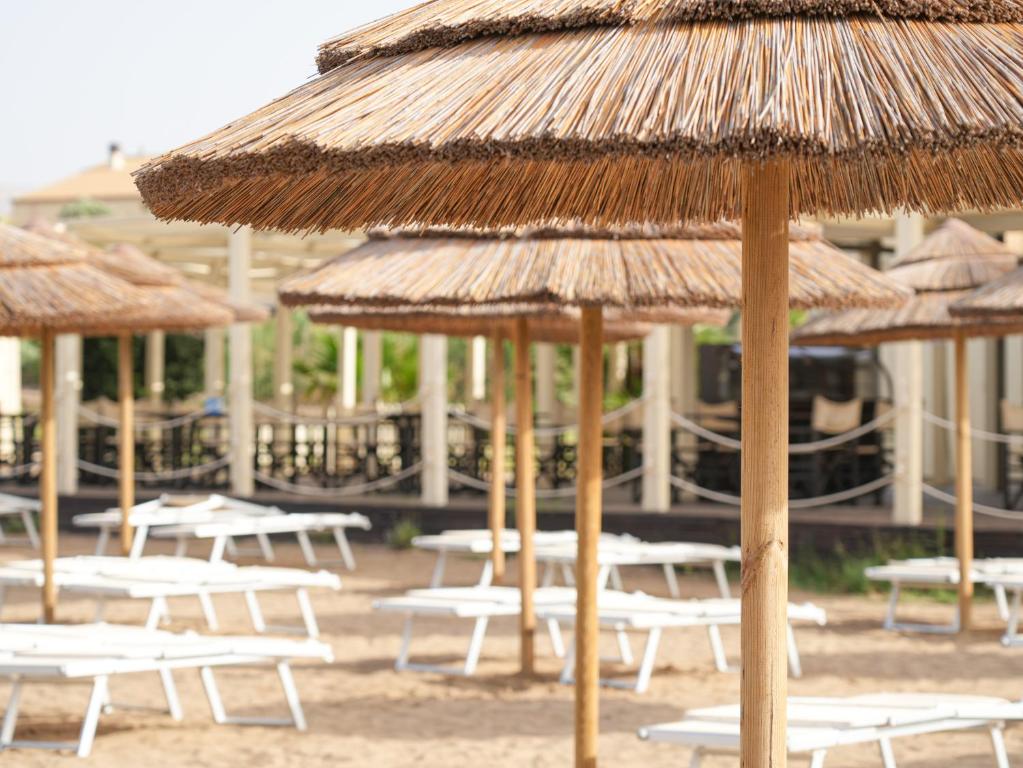 Pludmales atpūtas zona ar salmu saulessargiem un baltām atpūtas krēslām. Ideāla vieta relaksācijai un vasaras baudu izbaudīšanai.