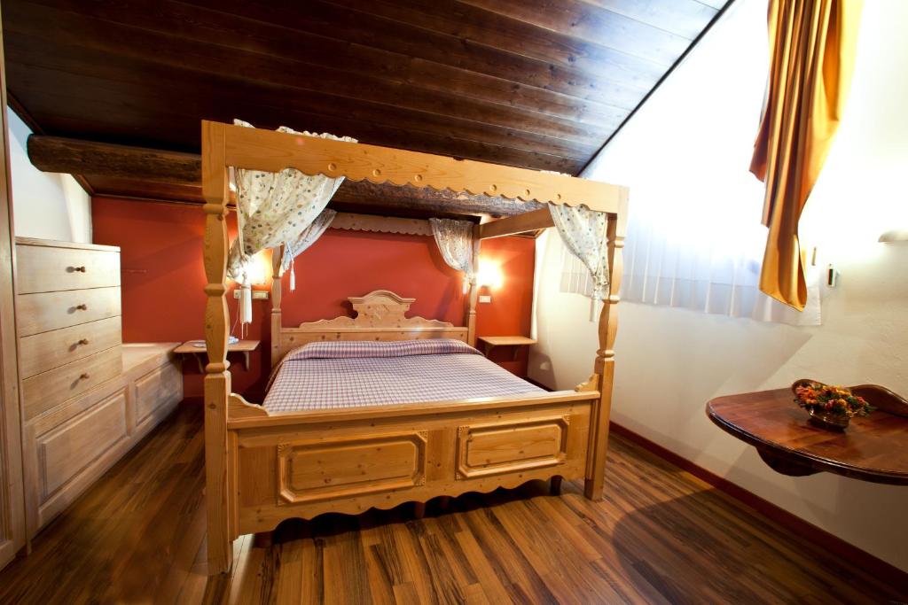 Mūsdienīga guļamistaba ar četru stūru gultu, koka mēbelēm un siltu krāsu paleti. Telpā ir dabiska apgaismojuma avoti un patīkama atmosfēra.