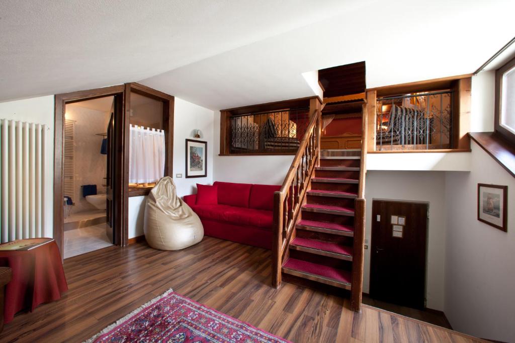 Moderns interjers ar sarkanu dīvānu, kāpņu telpu un piekļuvi vannas istabai, kas nodrošina mājīgu atmosfēru. Koka elementu un siltu toņu kombinācija rada patīkamu vidi.