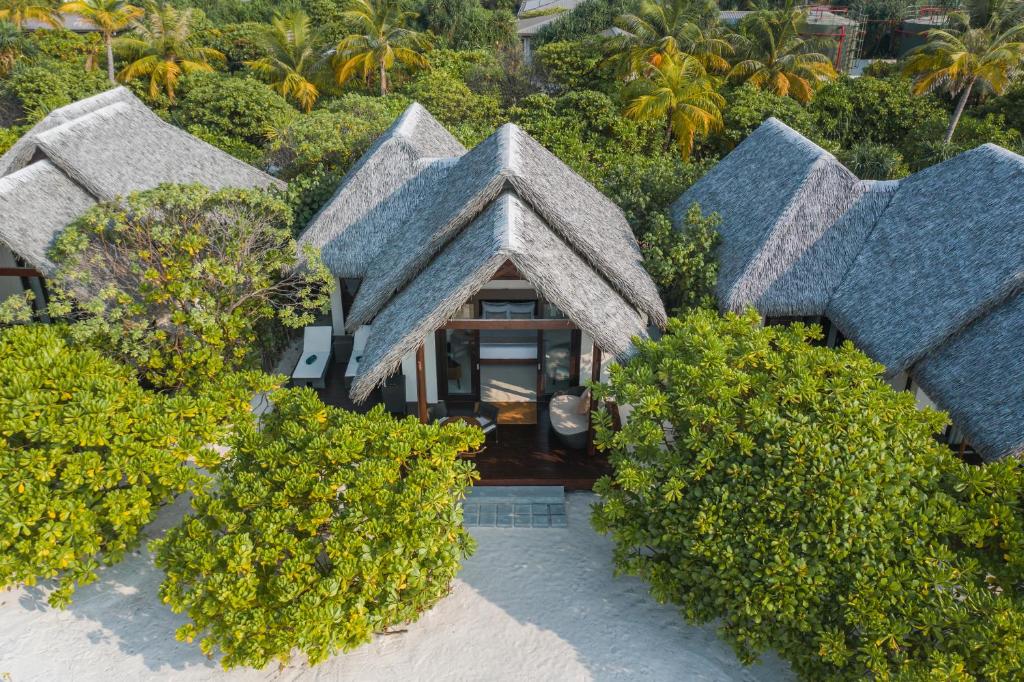 Tropu villas ar salmu jumtiem, ieskautas zaļo koku un palmu ainavā, piedāvā mierīgu un atpūtu veicinošu atmosfēru.