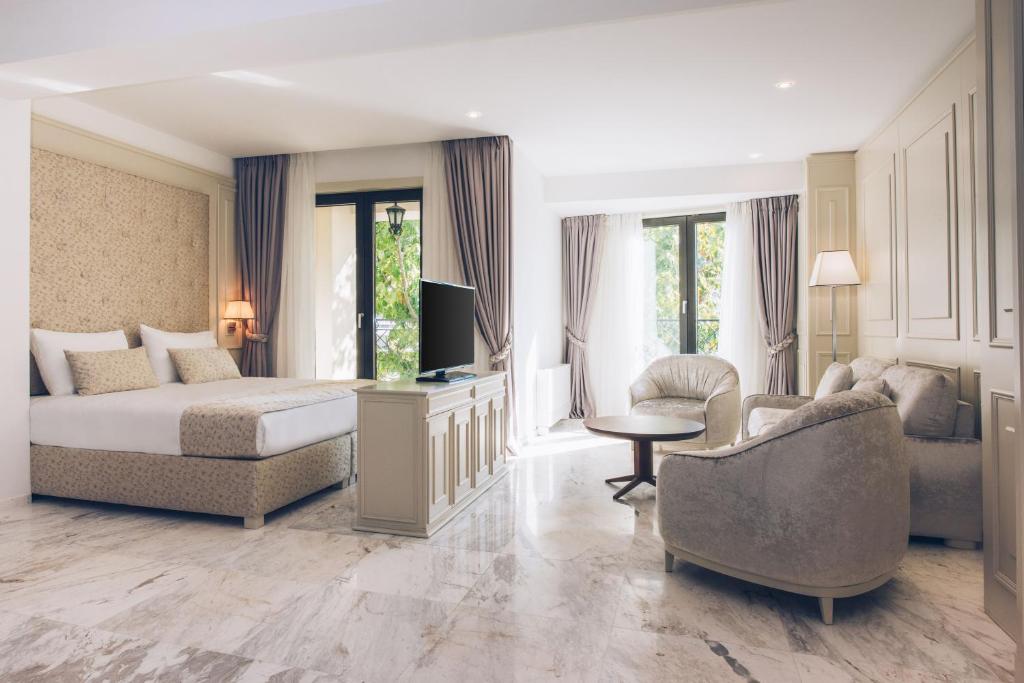 Mūsdienīga viesnīcas numura iekārtojums ar gultu, televizoru un komfortablām mēbelēm. Lieli logi nodrošina dabisko apgaismojumu un skatu uz dārzu.