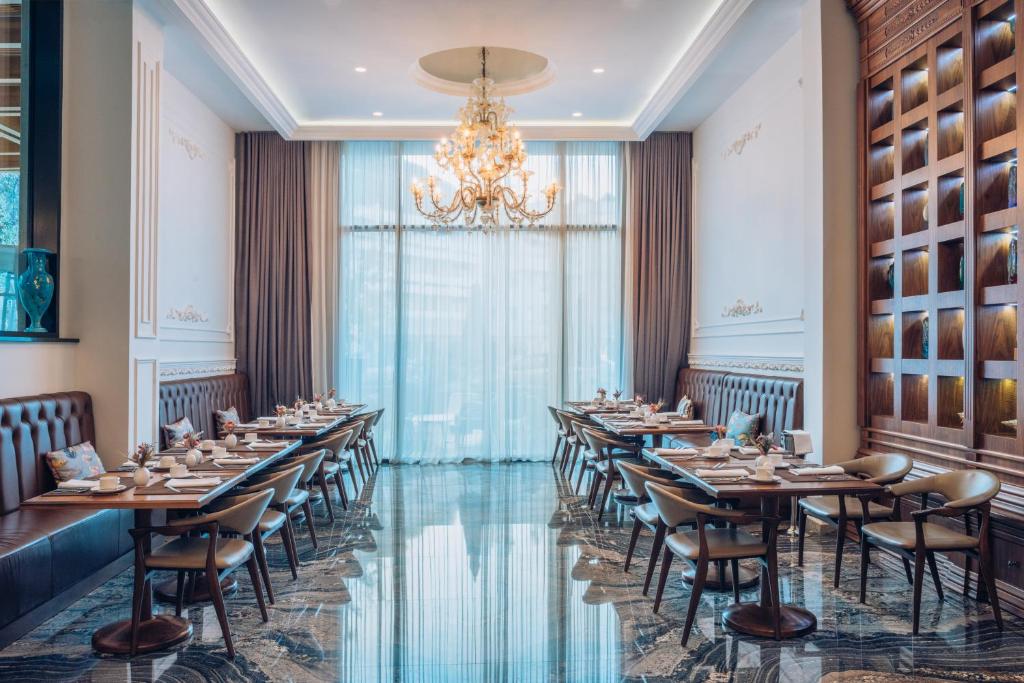 Eleganta restorāna iekārtojums ar modernām mēbelēm un lustru, kas rada patīkamu atmosfēru. Telpa ir gaiša un plaša, ar lieliem logiem un izsmalcinātiem dekoratīviem elementiem.