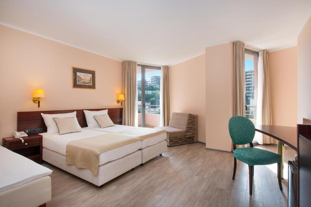 Mūsdienīgs viesnīcas numurs ar divām gultām, rakstāmgaldu un ērtu sēžamo stūrīti. Telpā ir lieli logi, kas nodrošina dabisko apgaismojumu.