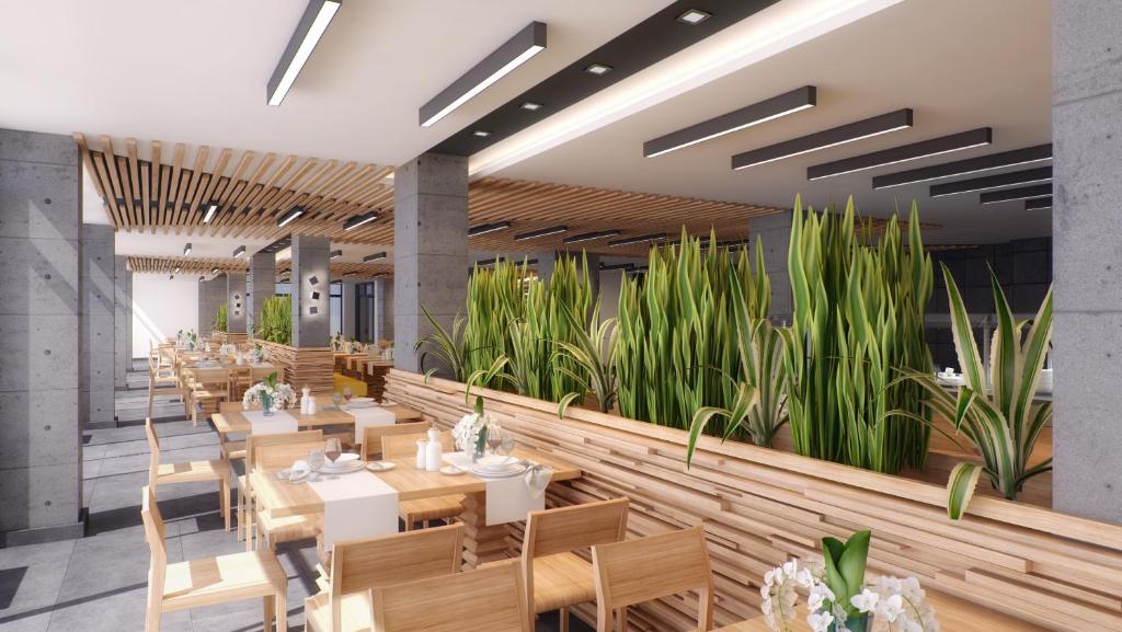 Mūsdienīgs restorāna interjers ar koka mēbelēm, rūpīgi izkārtotām galdiem un augiem, kas piešķir dzīvīgumu telpai. Apgaismojums rada patīkamu atmosfēru.