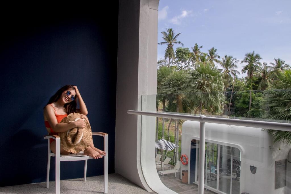 Sieviete sēž uz krēsla pie Sugar Marina Nautical, turot cepuri