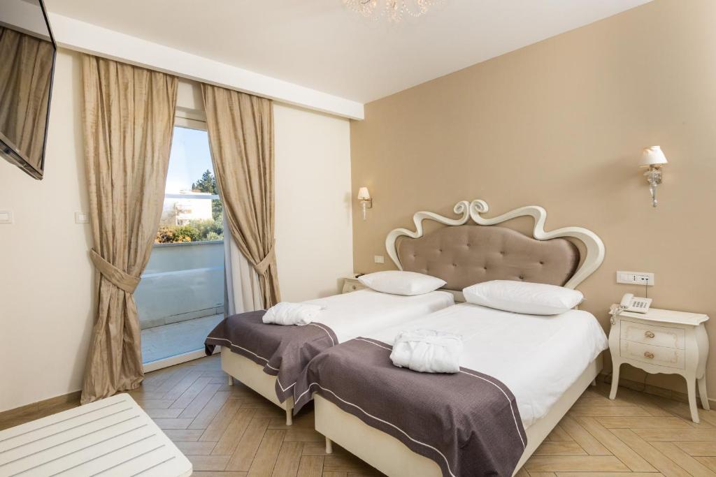 Mūsdienīga viesnīcas istaba ar divām atsevišķām gultām, elegantu interjeru un balkonu. Telpā ir televizors, ērti gultas piederumi un mīksti aizkari.