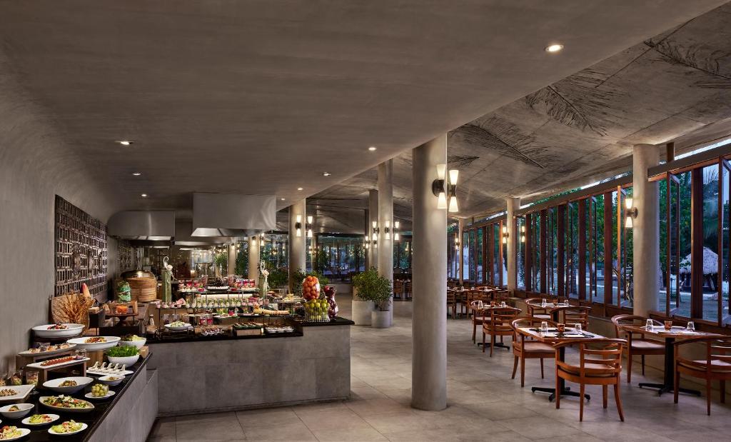 Mūsdienīgs restorāns ar plašu bufeti, kurā ir dažādi ēdieni un dzērieni, kā arī gaiša, atvērta telpa ar lielām logu sienām un koka mēbelēm.