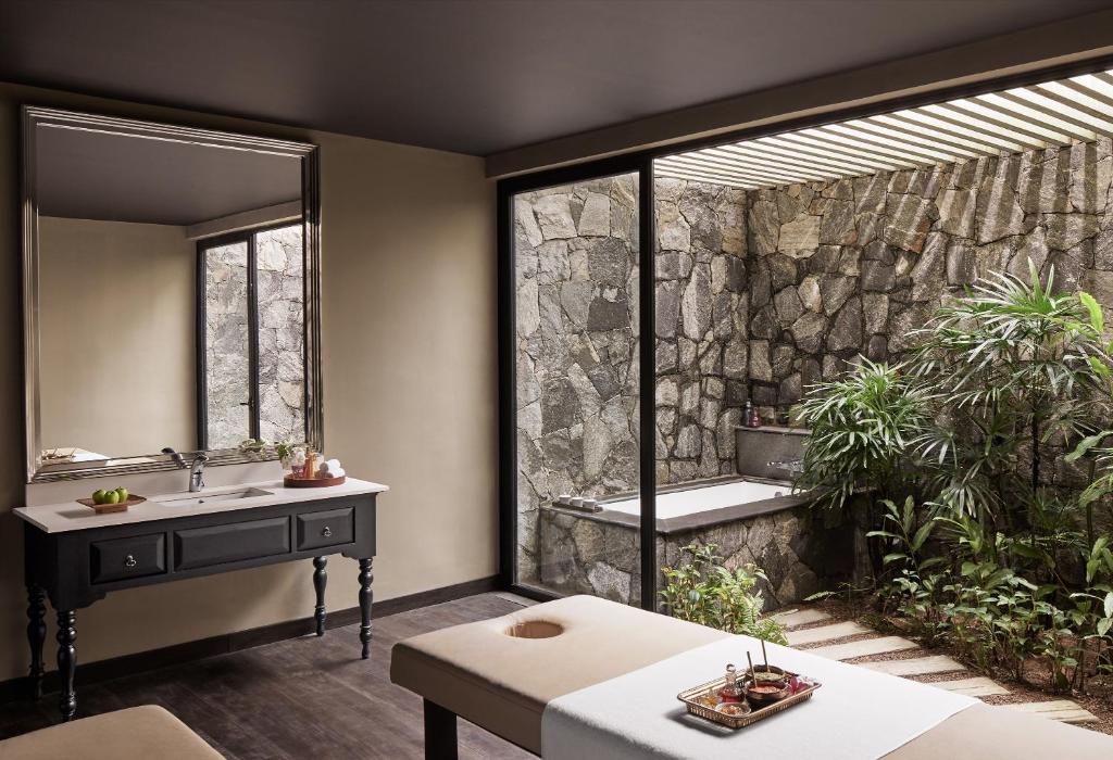 Elegants spa telpas interjers ar akmens sienu, vannu un masāžas galdu. Dabas elementi un mūsdienīgs dizains rada relaksējošu atmosfēru.