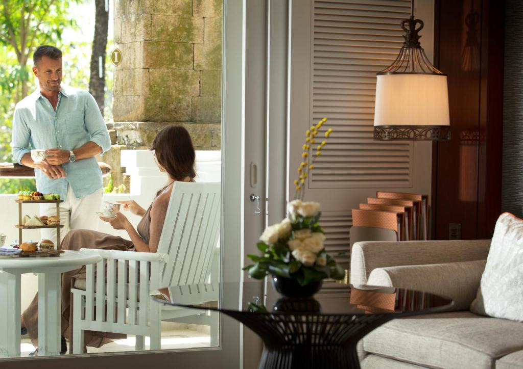 Eleganta pāra brīdis, baudot tēju un gardumus, iekārtojumā ar dabīgām gaismām un mūsdienīgu dekoru. Galda centrā ir uzkodu stends ar dažādām delikatesēm.