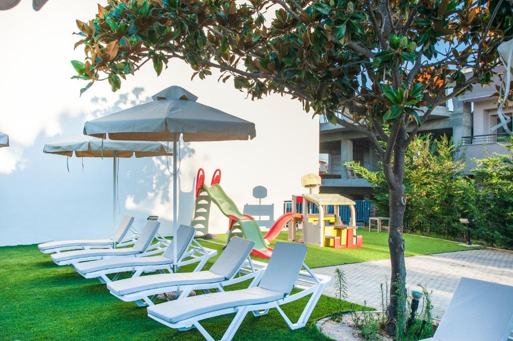 Atpūtas zona ar sauļošanās krēsliem un lietussargiem, blakus bērnu rotaļu laukumiem un zaļai zālienai. Ideāla vieta ģimenēm un atpūtai brīvā dabā.