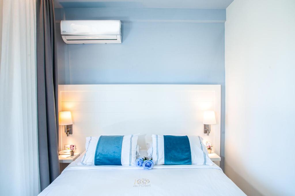 Mūsdienīga guļamistaba ar gaismu, baltu gultu un zilām akcentu spilveniem. Gaismas piekare un elegantas aizkaru krāsas radījušas relaksējošu atmosfēru.