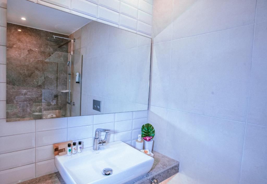 Moderns vannas istabas interjers ar baltu izlietni, spoguli un dušas kabīni, papildināts ar augu dekoru.