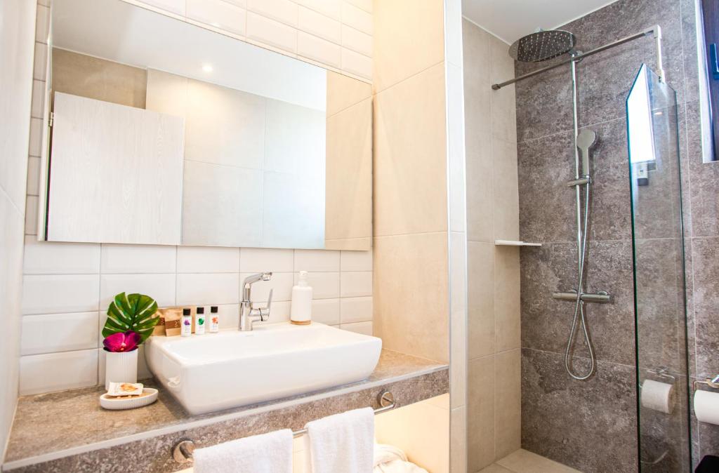 Mūsdienīgs vannas istabas interjers ar elegantu izskatu, iekļaujot dušas zonu, izlietni un skaistus aksesuārus. Svaigas augu detaļas piešķir dzīvīgumu.