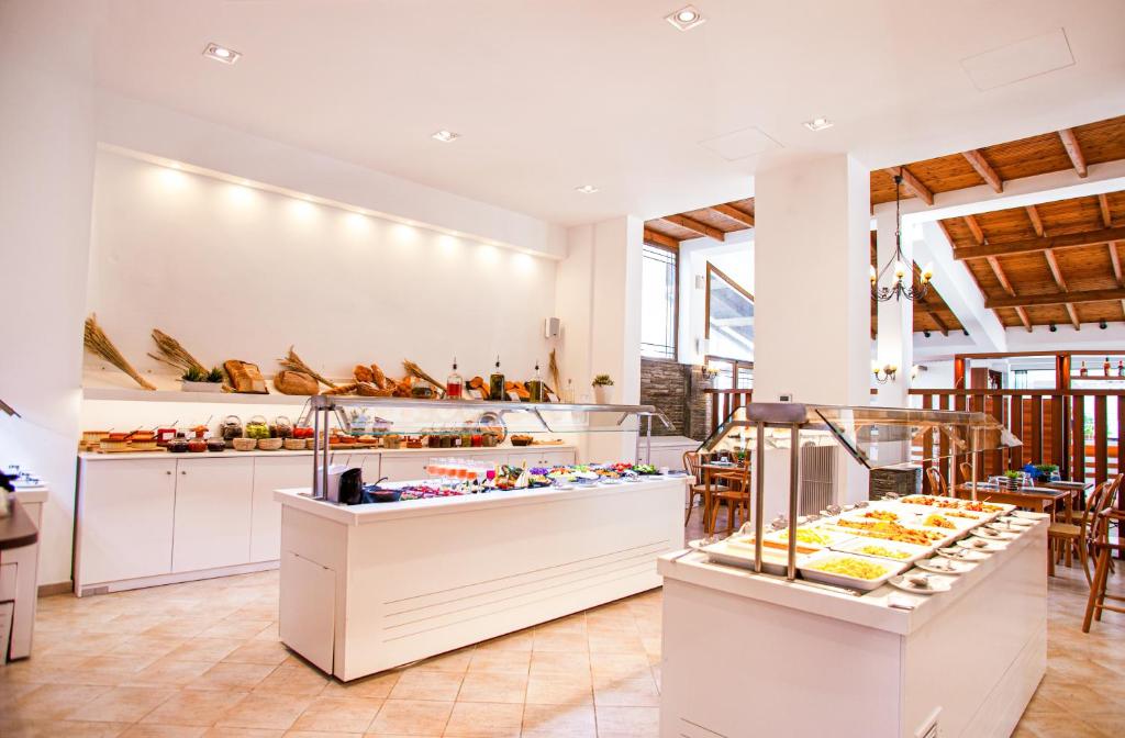 Gaismas un mūsdienīga restorāna interjers ar bagātīgu bufeti, kurā redzami dažādi ēdieni un saldumi. Svaigi produkti un dekora elementi rada viesmīlīgu atmosfēru.