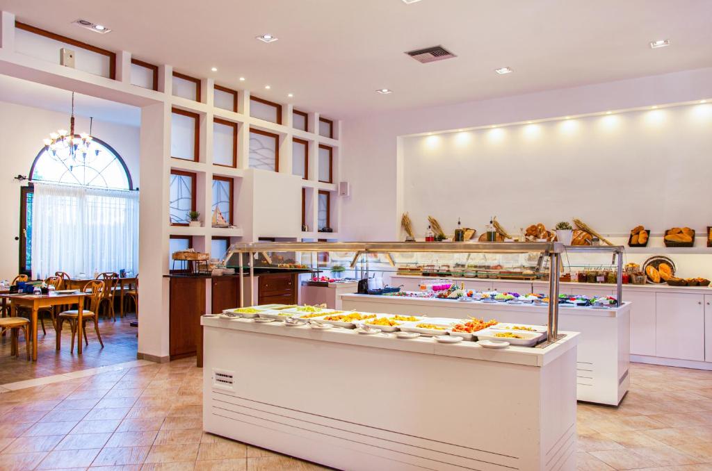 Mūsdienīga restorāna iekšskats ar bufeti, kas piedāvā dažādus ēdienus, un koka galdiem apkārt. Lielas logu vitrāžas un mājīga atmosfēra.