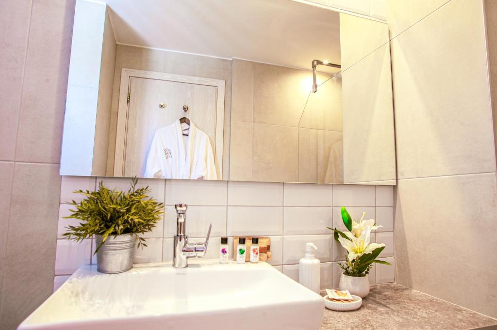 Moderns vannas istabas interjers ar izsmalcinātu izskatu, kas ietver spoguli, izsmalcinātu izlietni un dekoratīvās augu kompozīcijas. Vannas istaba ir gaiša un eleganta, radot relaksējošu atmosfēru.