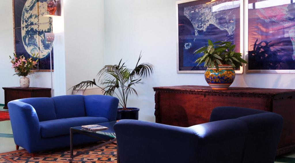 Rada Siri Hotel mūsdienīgs vestibils ar zilu dīvānu un mākslas darbiem.