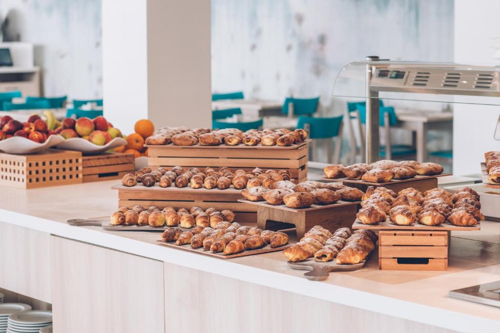 Maizes izstrādājumi un augļi ir izkārtoti uz galda kafejnīcā, piedāvājot dažādas gardas uzkodas. Gaisīga un moderni iekārtota vide rada patīkamu atmosfēru.