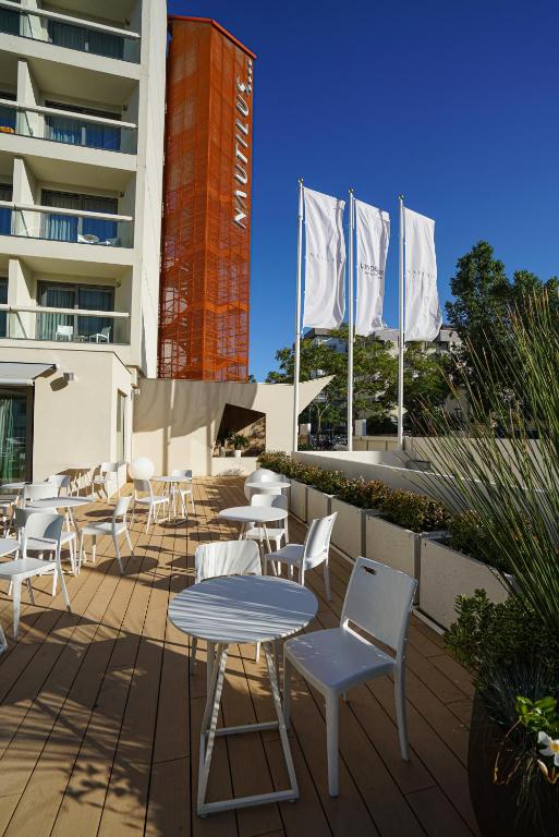 Terase ar baltām mēbelēm un oranžu ēku fona, kur plīvo balti karogi. Ideāla vieta atpūtai un relaksācijai.