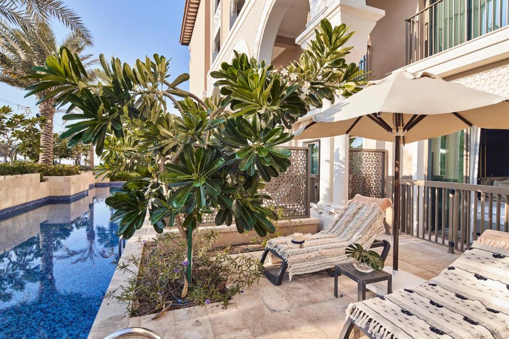 Trokšņaina zona ar baseinu, saules krēsliem un lapenēm, kas ieskauj tropiskās augu kompozīcijas. Ideāla vieta relaksācijai un atpūtai.