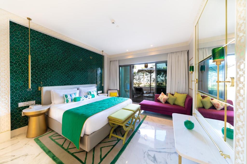 Mūsdienīgs viesnīcas numurs ar zaļiem un rozā akcentiem, iekārtots ar elegantu mēbeļu un dekoru kombināciju. Telpa ir gaiša un plaša, ar lieliem logiem, kas nodrošina dabisko apgaismojumu.